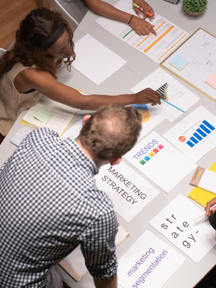 hero-img-02 Team discussing marketing strategies in a modern office setting with charts and documents.